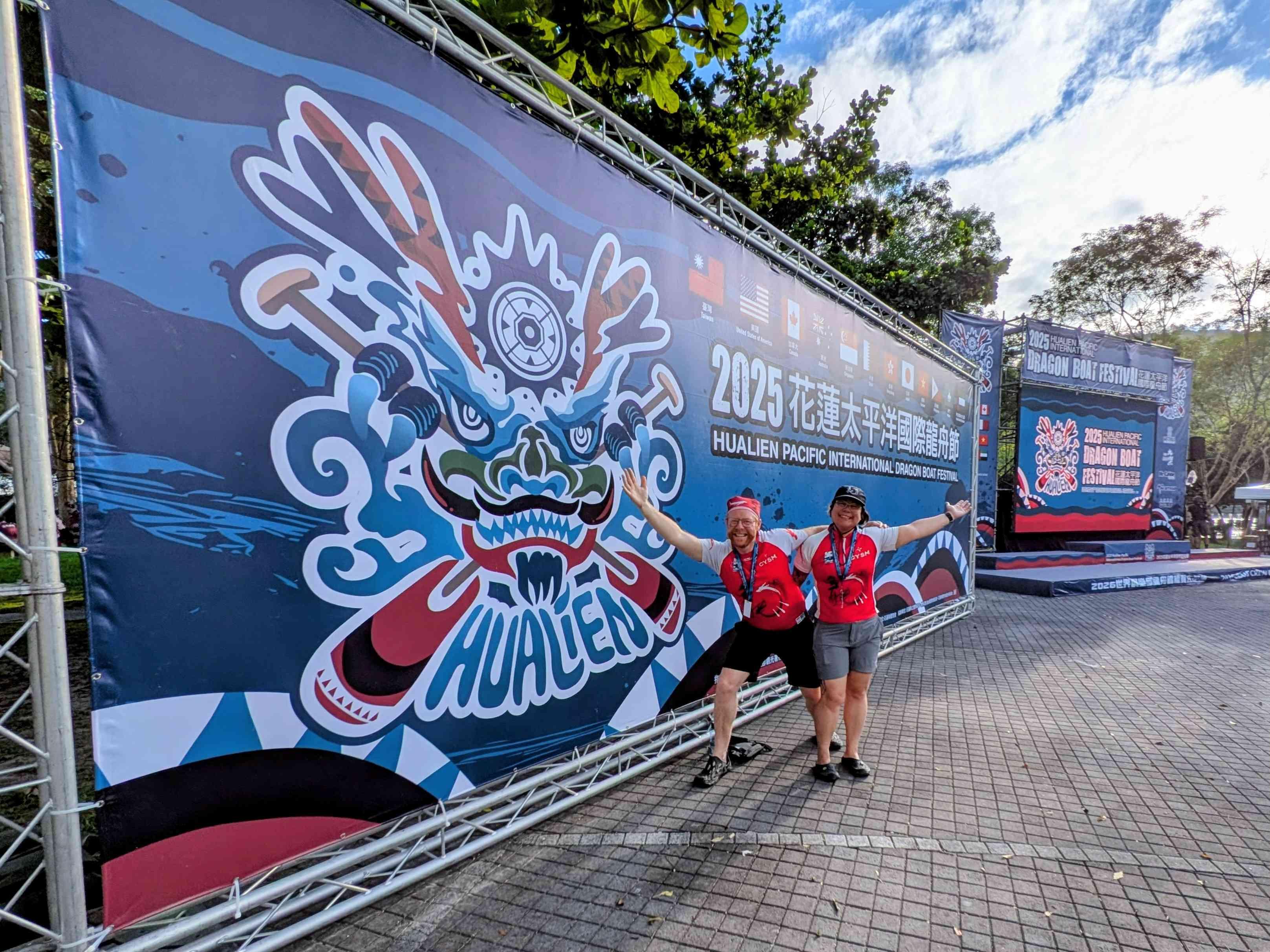 My partner and I are standing in front of a giant Hualien dragon boat regatta banner